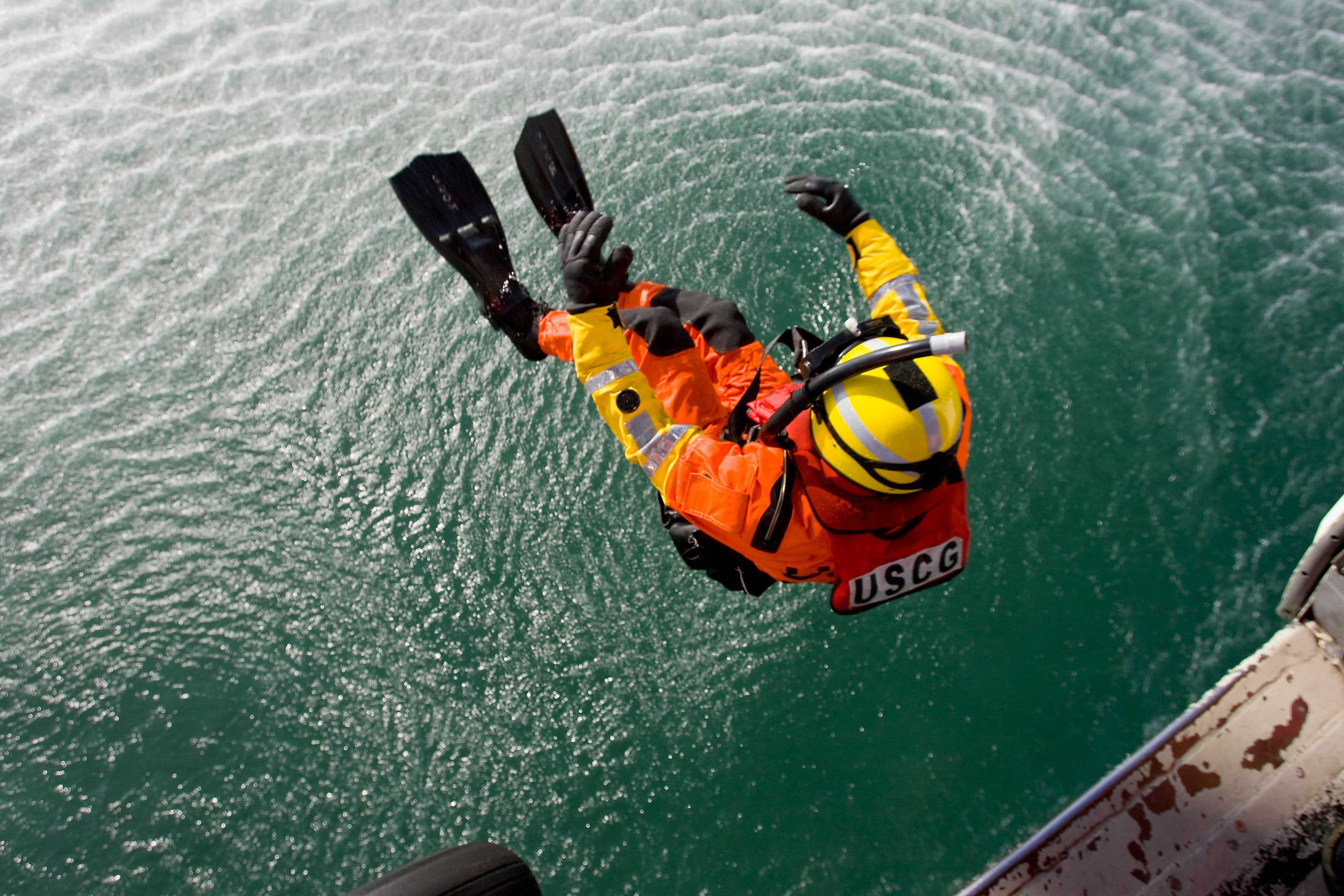 USCG rescue swimmer jumping into ocean water from helicopter