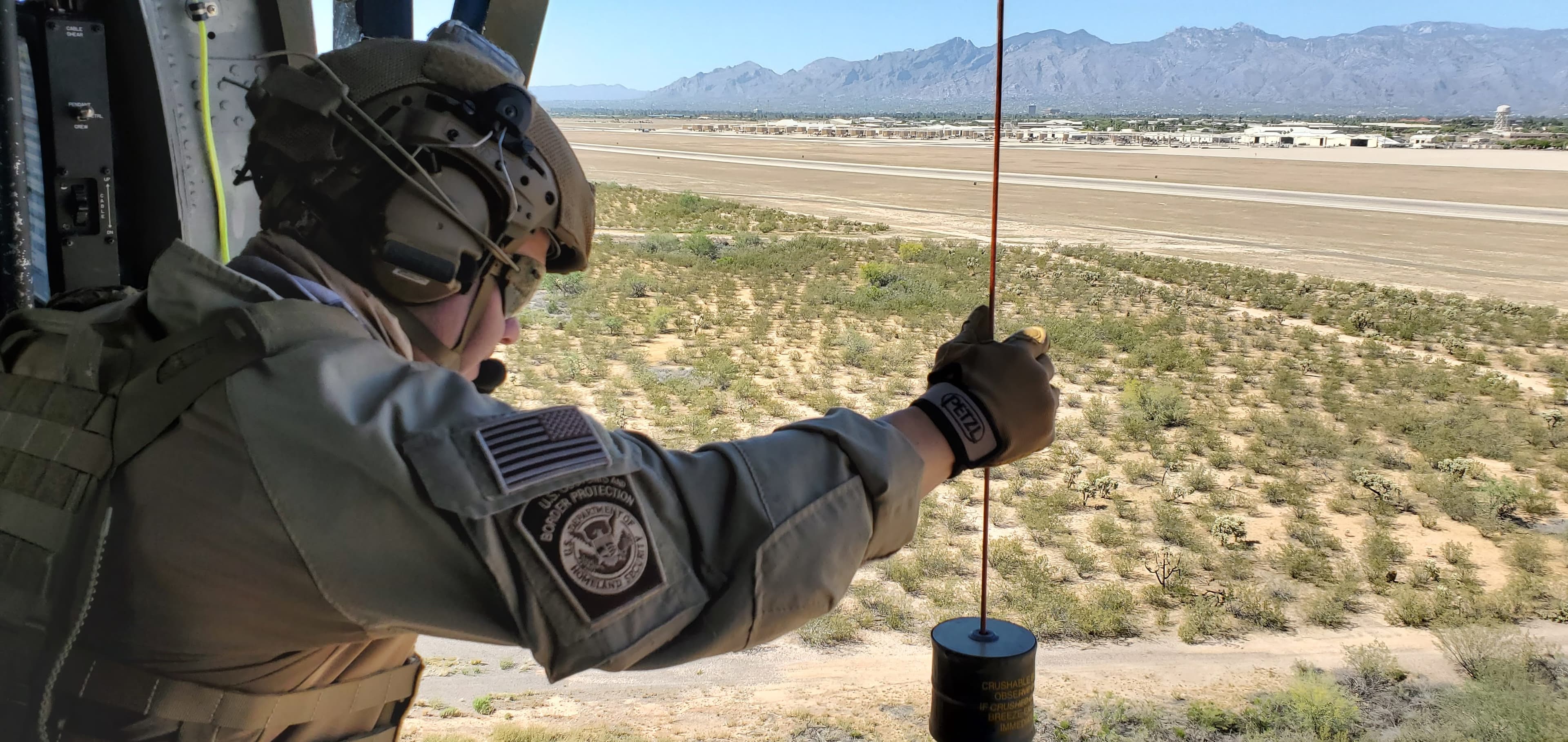 CBP hoist operator in desert landscape from helicopter