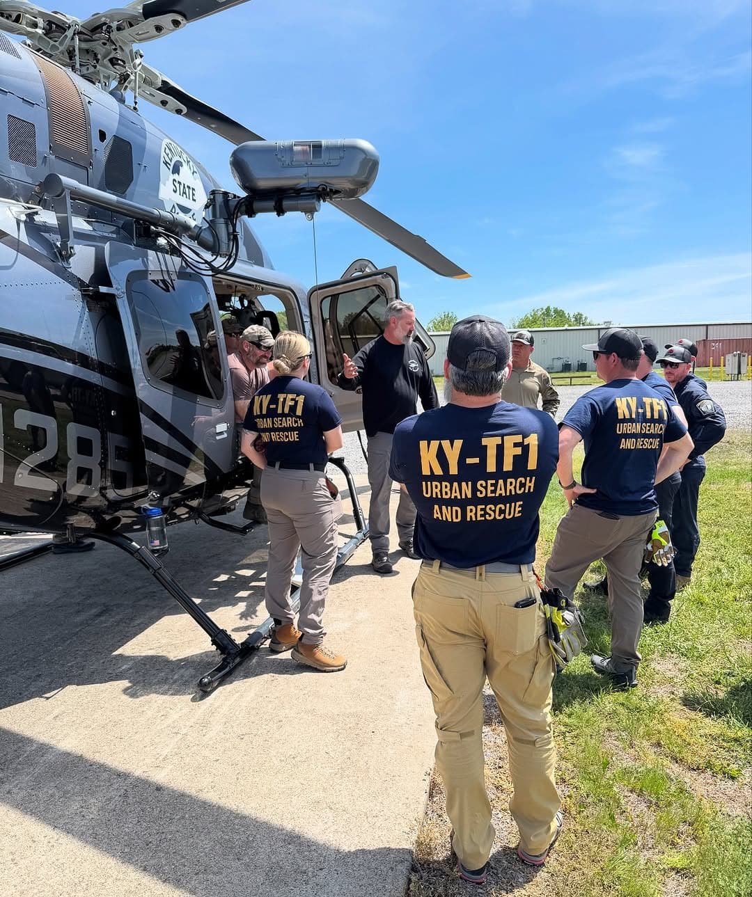 Kentucky State Police and KY-TF1 rescue crew briefing beside a hoist-equipped helicopter